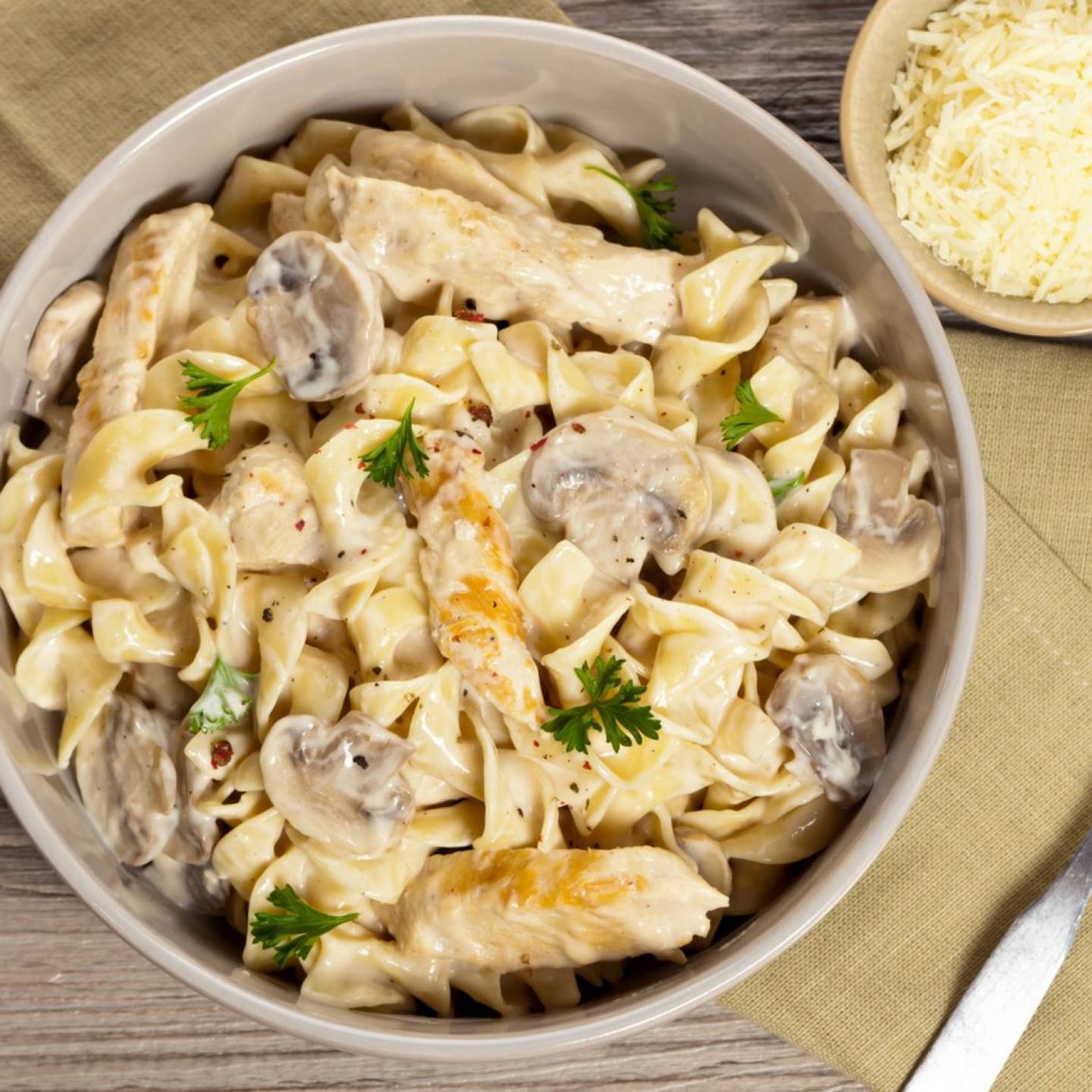 Chicken and Mushroom Pasta in a creamy sauce in a pan with a napkin on the side.