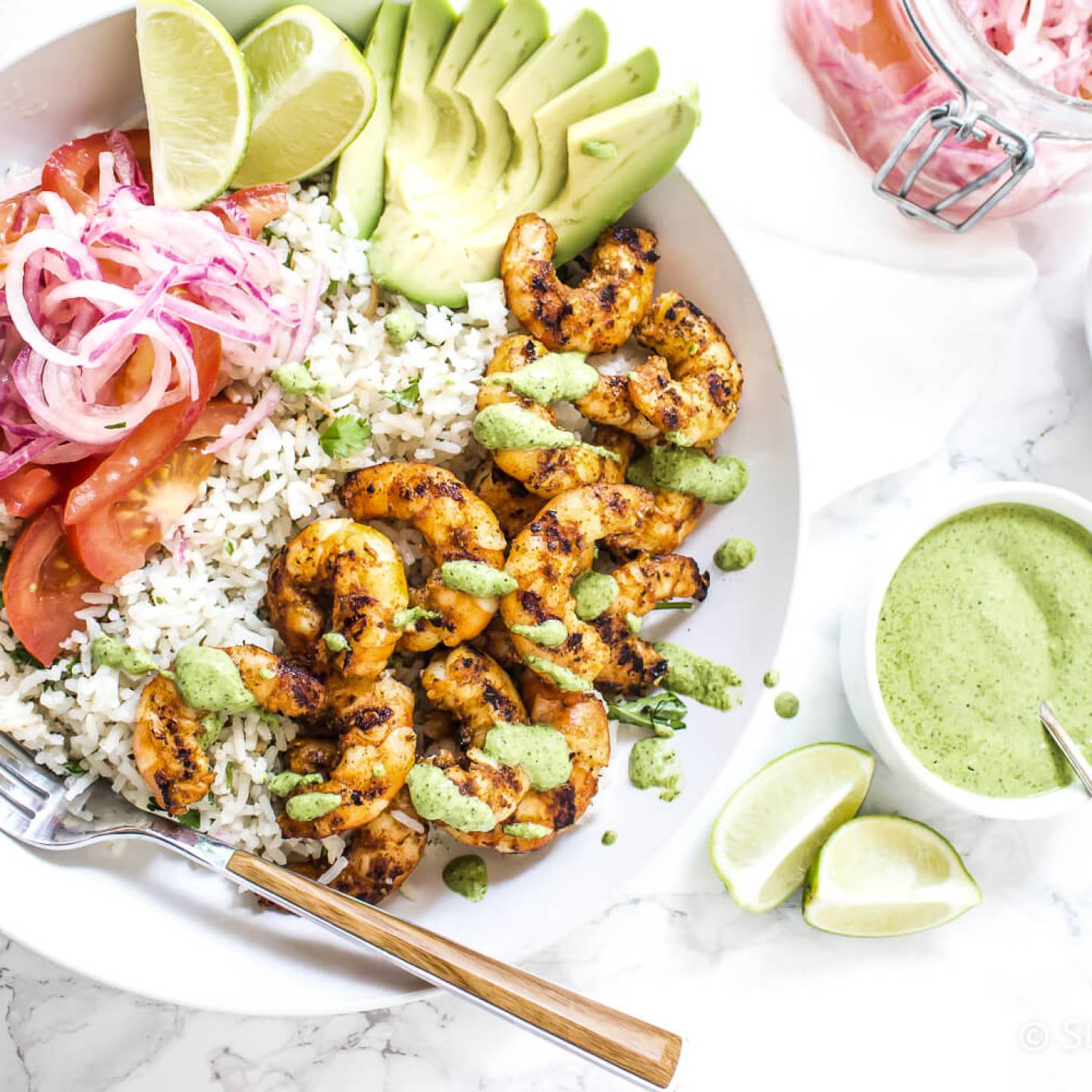 Peruvian shrimp rice bowls with grilled shrimp, white rice, cilantro mint sauce, salsa criolla, and sliced avocado.