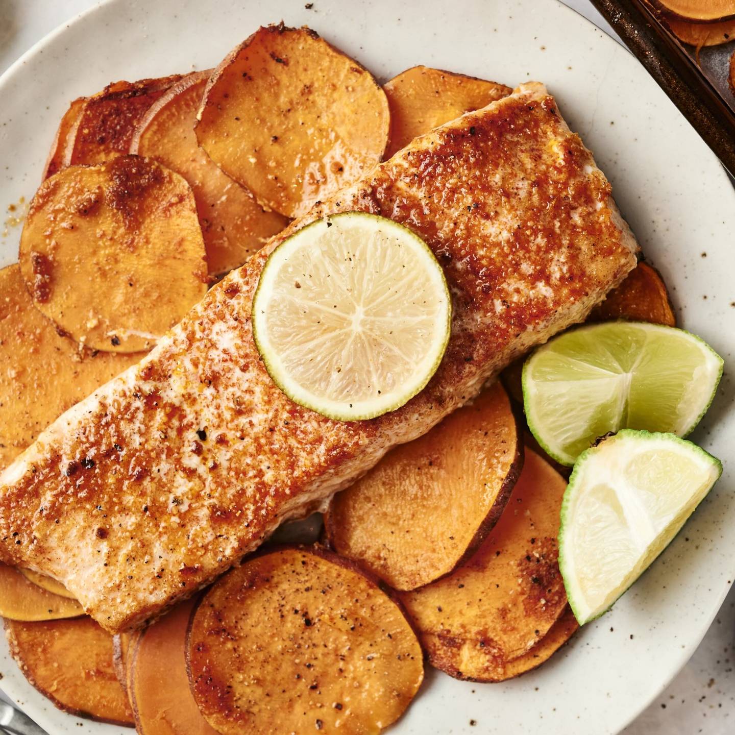 Spiced salmon fillet with a lime slice, served over roasted sweet potatoes.