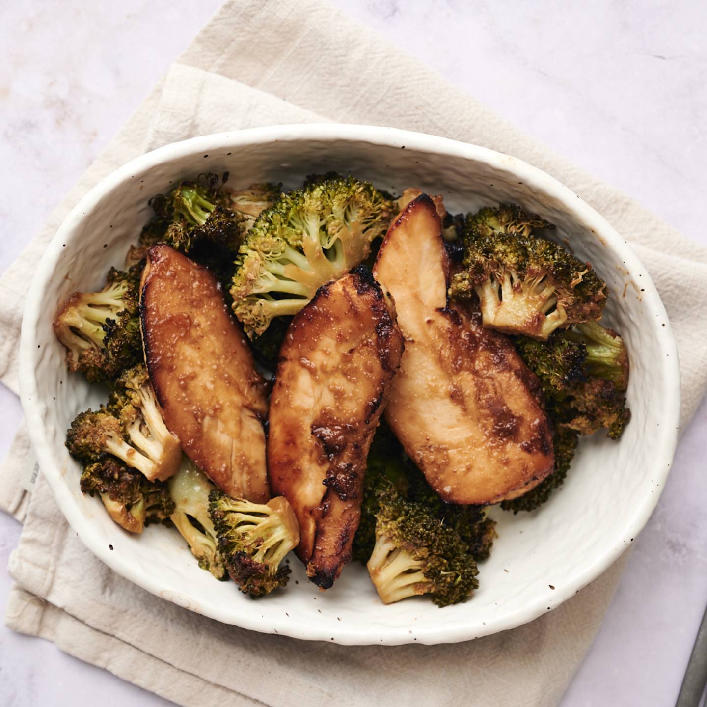 Sheet pan peanut chicken and broccoli with peanut sauce on a baking sheet.