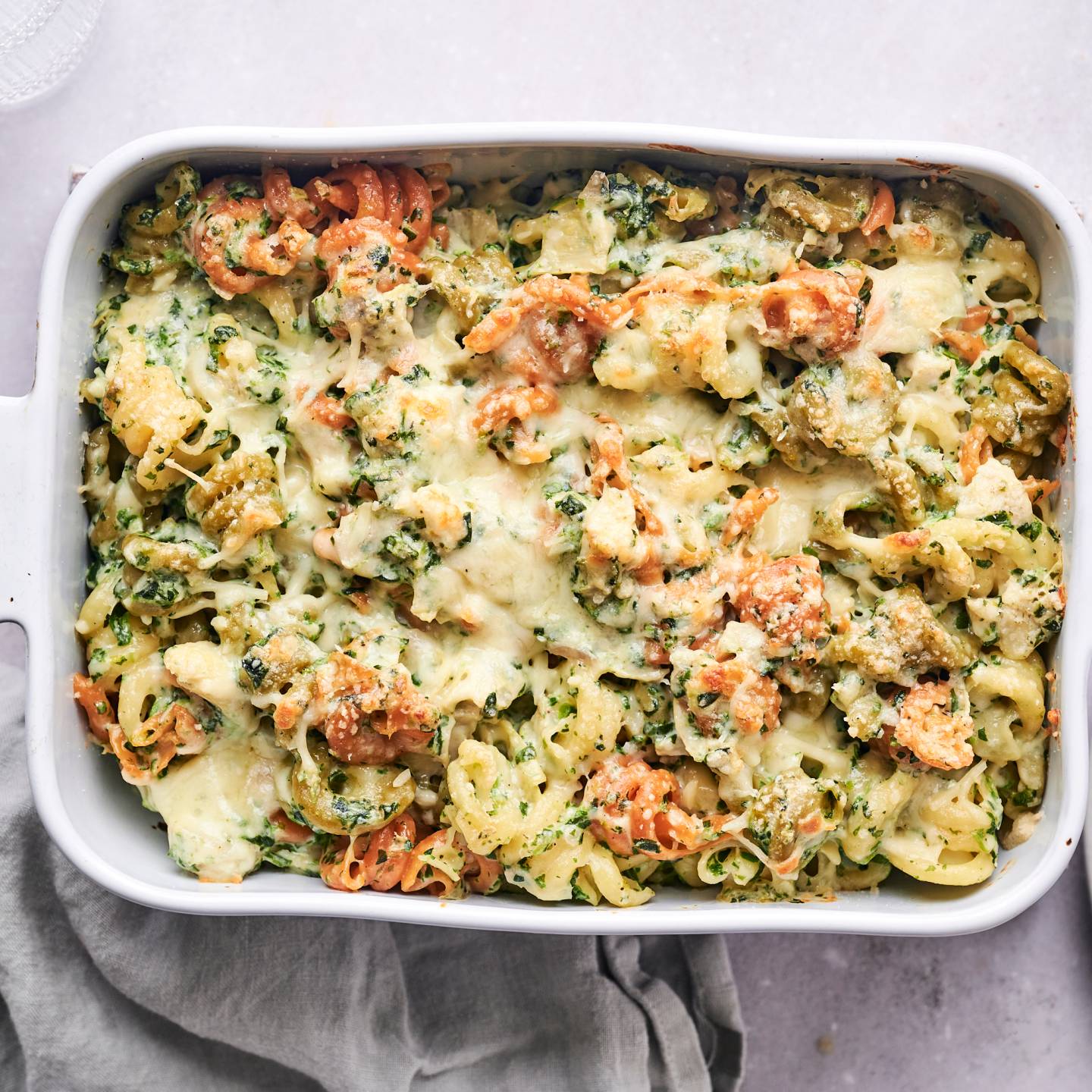 Spinach artichoke pasta with melted cheese in a casserole dish.