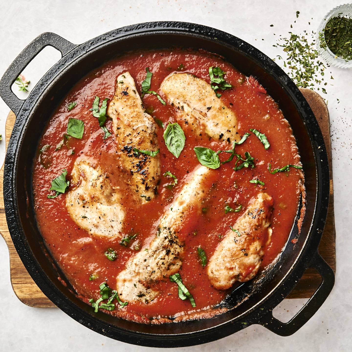Tomato basil chicken with chicken breast served in a hearty tomato sauce with basil in a heavy skillet.