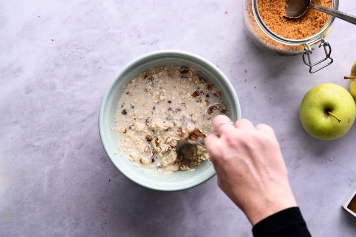 Rolled oats, walnuts, milk, and spices in a bowl.