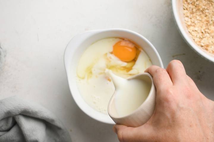 Eggs, almond milk, bananas, maple syrup, and vanilla extract in a bowl.