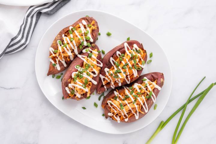 Buffalo chicken stuffed into sweet potatoes and drizzled with ranch dressing.