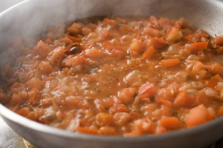 Diced tomatoes and chipotle peppers simmering in a skillet for chicken tinga sauce. 