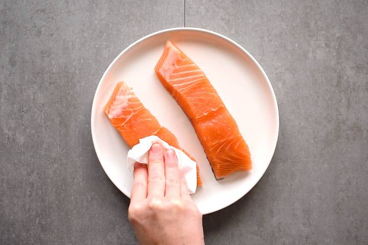 Salmon filets being dried with a paper towel.