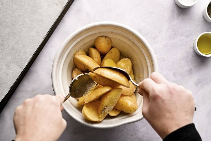 Bowl with fingerling potatoes, olive oil, salt, pepper, and spices.