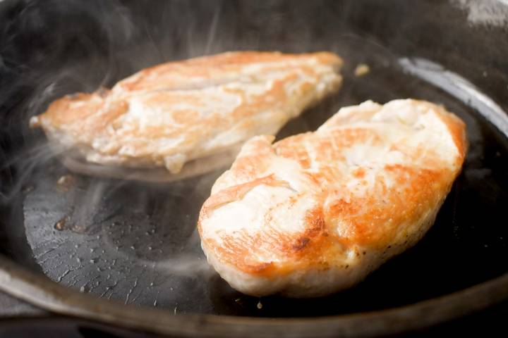 Chicken breast searing in a pan.