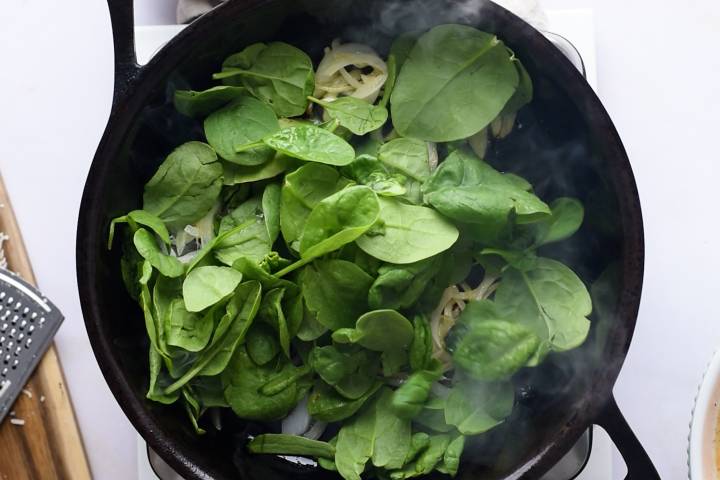 Spinach and onions cooking in a skillet.