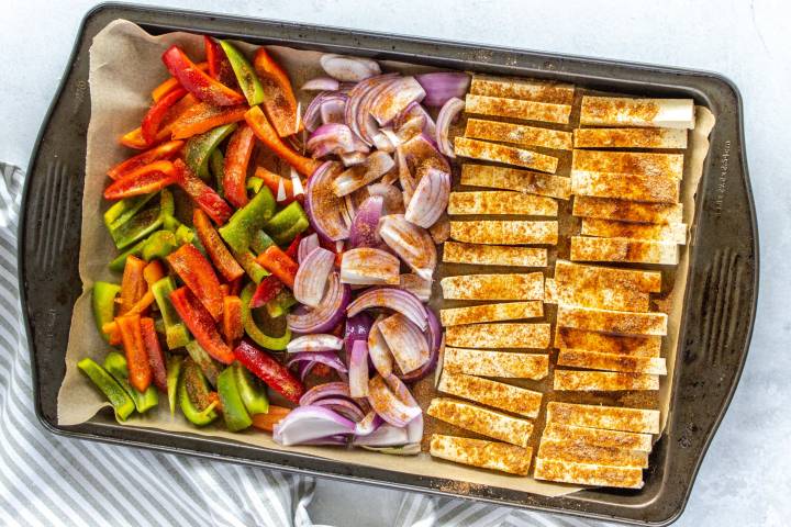 Fajitas with tofu, bell peppers, and red onions on a baking sheet,