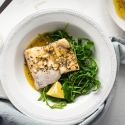 Easy baked cod with a lemon, garlic, and butter sauce on a white plate with mixed greens.