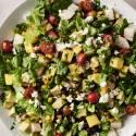 A vibrant Mexican chopped salad filled with diced mango, avocado, cherry tomatoes, black beans, corn, jicama, romaine lettuce, and crumbled cheese, garnished with fresh cilantro on a white plate.