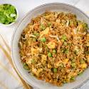 Quinao fried rice with peas, cabbage, eggs, and soy sauce in a bowl with chopsticks.