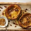 Roasted acorn squash with butter, brown sugar, and cinnamon on a baking sheet.