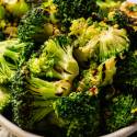 A bowl of roasted broccoli florets garnished with lemon zest and chili flakes. 